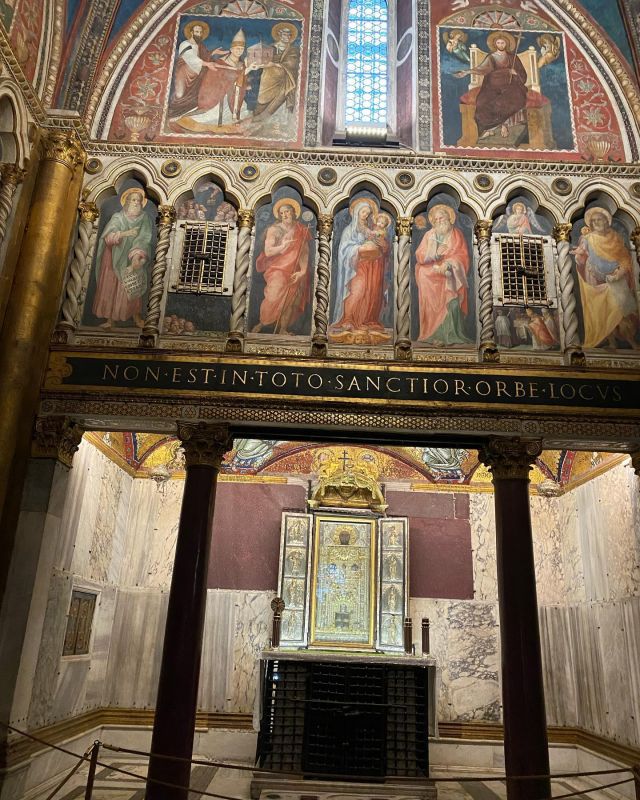 After climbing the last step, the pilgrim finds himself in front of the iron grating which protects the Sancta Sanctorum. According to medieval historians, this was “the most venerated sanctuary in Rome” and was, until the Renaissance, the private oratory of the Popes. Today it remains a testament to the splendour of the ancient Patriarchium and to a thousand years of papal history. The founder of the chapel remains unknown; however it was originally dedicated to St. Lawrence, and in the IX century it was called the Sancta Sanctorum, due to the numerous important relics housed within. The most ancient and venerated object in the Sancta Sanctorum is the image of the Holy Saviour. Kept above the altar, it is referred to as the “Acheropita” (not made by human hands). Due to its importance, the Chapel is referred called by the name of this image in several documents. Painted on a wooden panel, the image of the Saviour is represented sitting on a throne, blessing with his right hand and holding the scroll of the Gospel in his left hand. The origins of the image remain unknown. Below the Papal altar, protected by an enormous wrought iron cage, lie two bronze doors, covered with reliefs and inscriptions dating from the 13th century. These decorations cover the cypress wood ark, specifically made by Leo III to contain the illustrious treasures and relics of the Sancta Sanctorum. In 1902, the grate was opened for the first time since 1521, after Father F. Jubaru S.J. got the permission to examine the head of Saint Agnes which was kept within. In 1905, F. H.Grisar, was allowed to open it once again to study the magnificent collection of sacred objects made of gold, silver, ivory, and precious woods, together with numerous relic holders, crosses, fabrics, brocades, parchments, miniatures and enamels, all of incalculable value – a veritable treasure chest. The reliquaries were transferred to the Sacred Christian Museum in the Vatican library. Among the relics kept at this site were the heads of the apostles Peter and Paul, which are now venerated in the Basilica of Saint John Lateran.